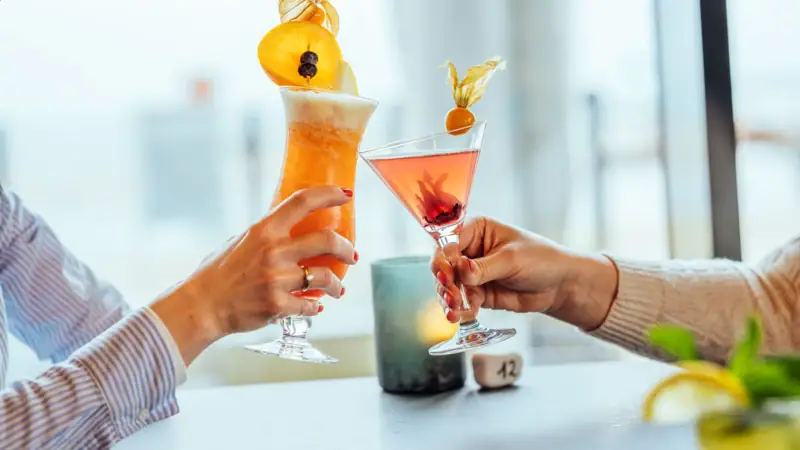 A pair of hands holds glasses with drinks.