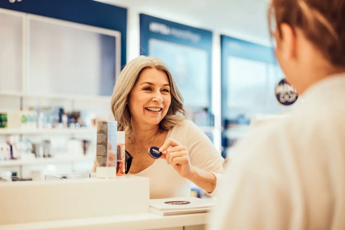 A woman smiles at a shop assistant at a counter