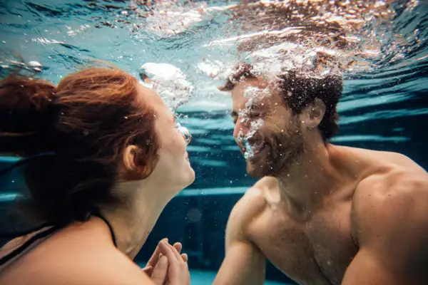 A man and a woman swim underwater.