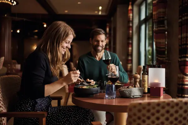 A man and a woman are eating at a table.
