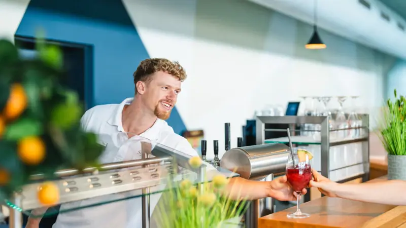 A man handing a drink to a woman in a kitchen setting.