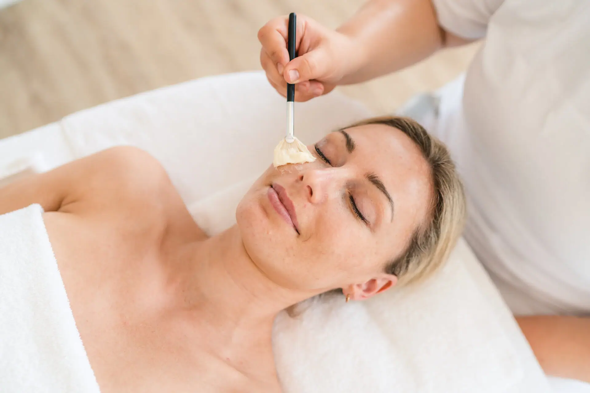 Cosmetics at aja Grömitz A woman lies with a paintbrush on her face.