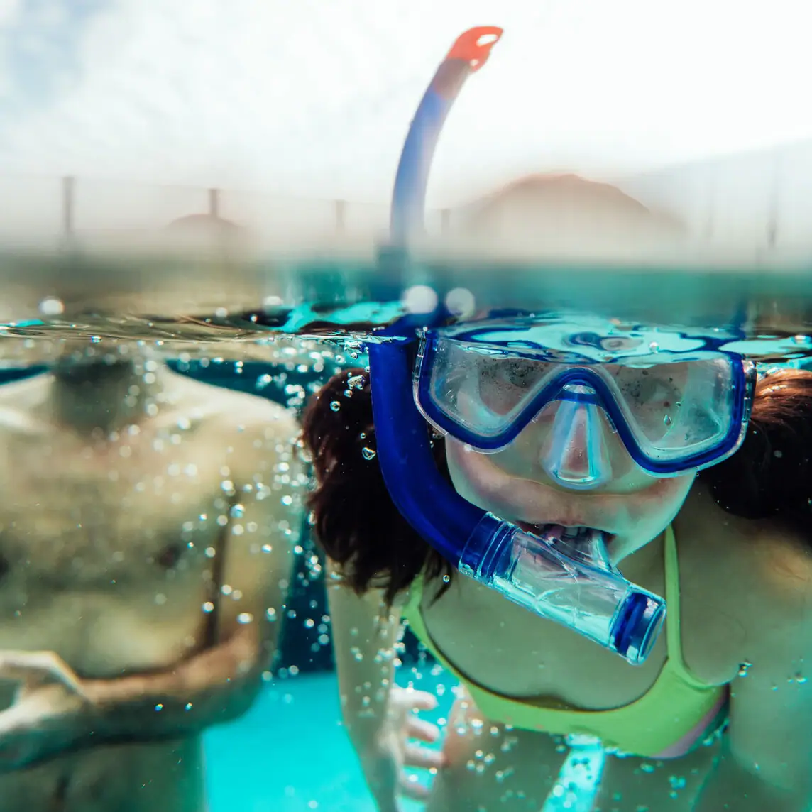 A child in a swimming costume and goggles under water.