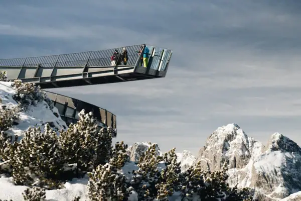 People crossing a bridge on a snowy mountain.