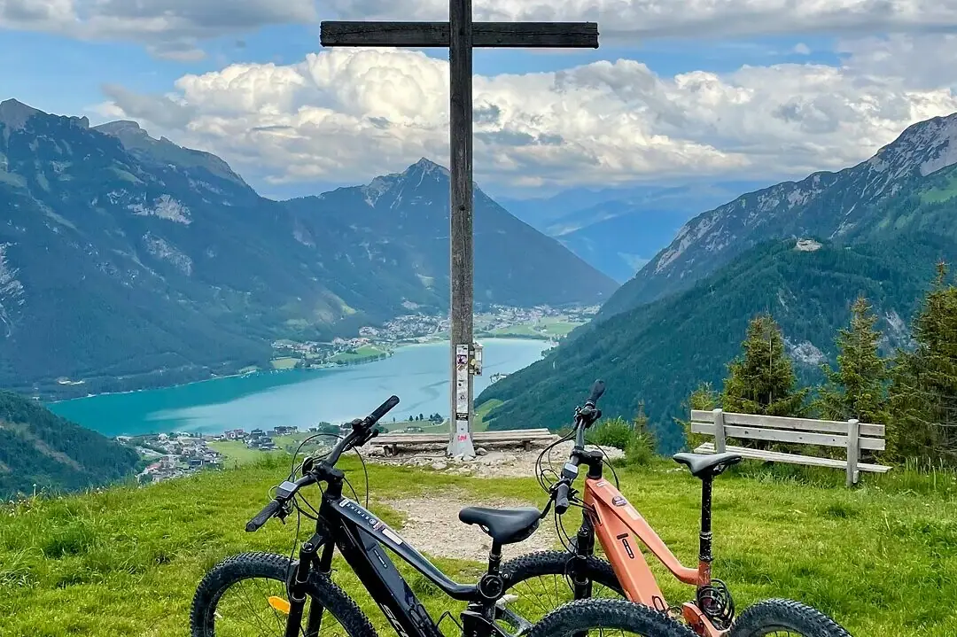 Summit cross Two bicycles on a hill with a cross in the background.