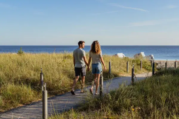 Walking on Usedom A man and a woman hold hands and walk along a path by the water.