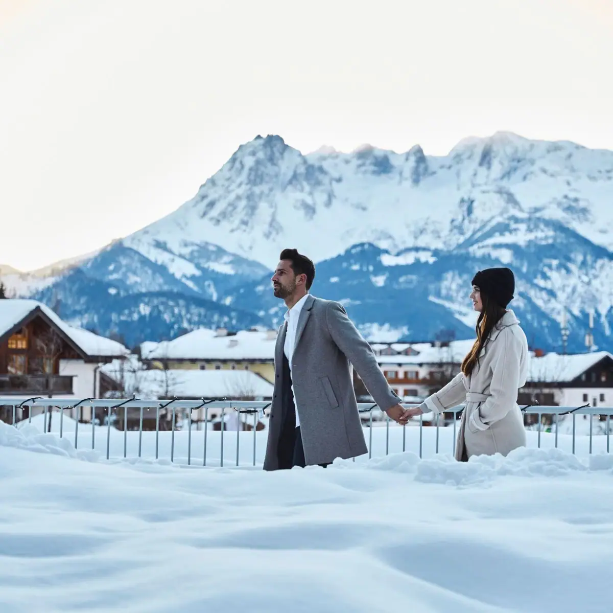 A man and a woman hold hands in the snow.