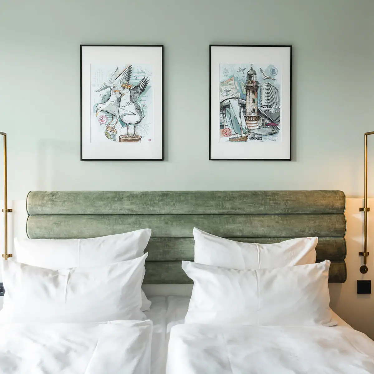 Bed with white cushions and green headboard, flanked by two lamps.