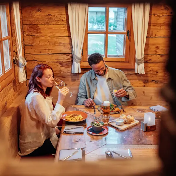 A man and a woman are sitting at a table with food and drink.