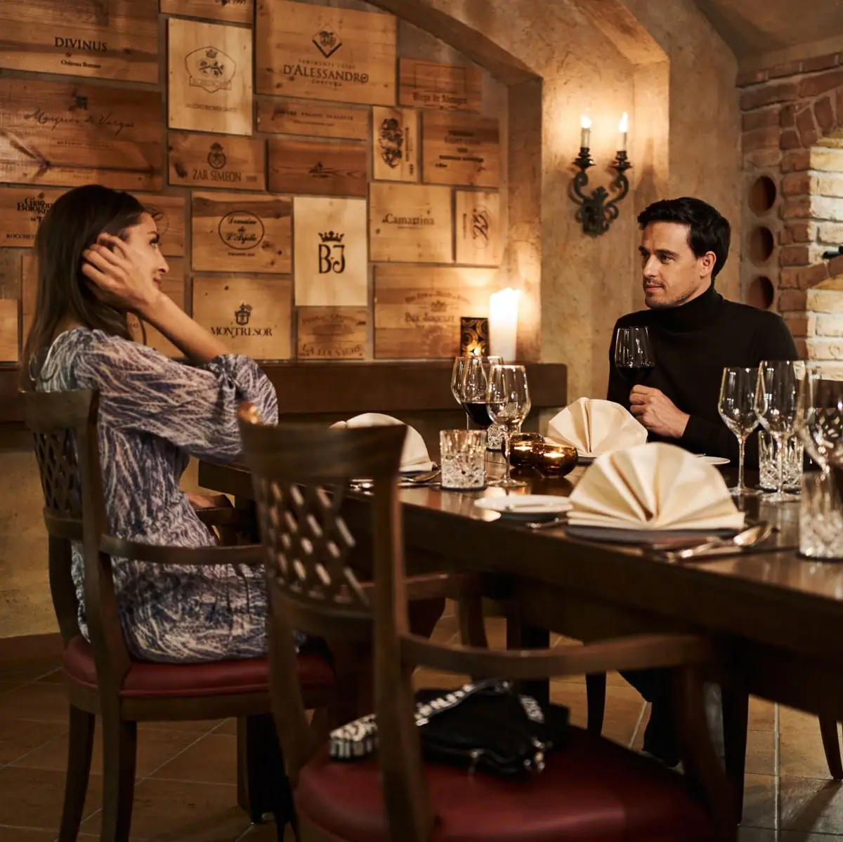 Dinner in the wine cellar A man and a woman are sitting at a table with glasses of wine.