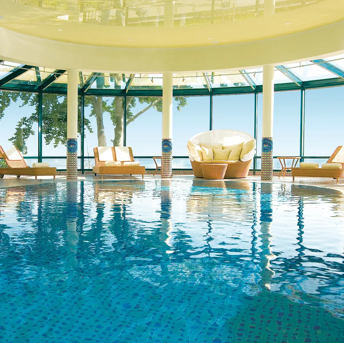 An indoor pool with chairs and a large ceiling.