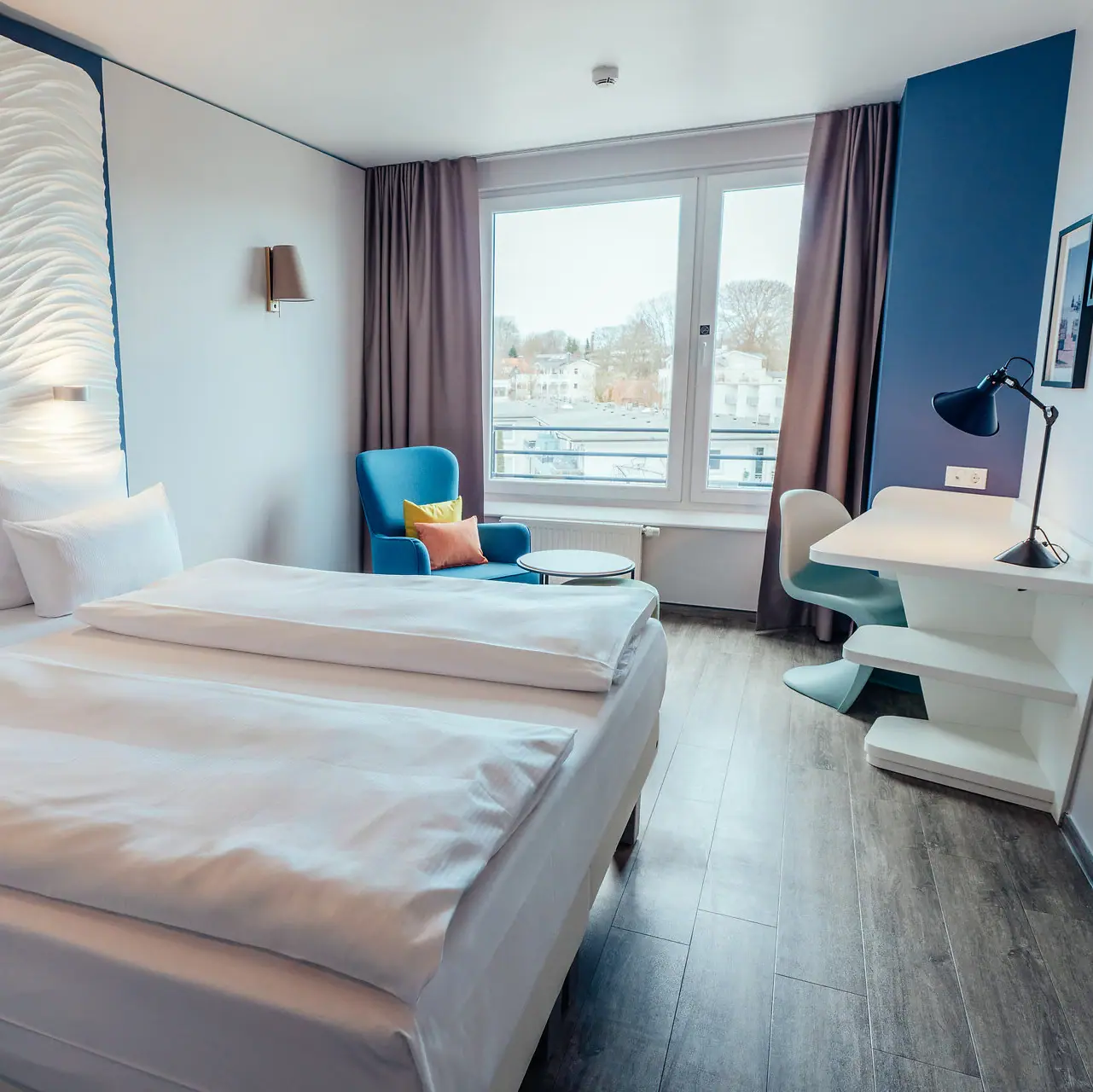 A room with two beds, a table, and pillows.