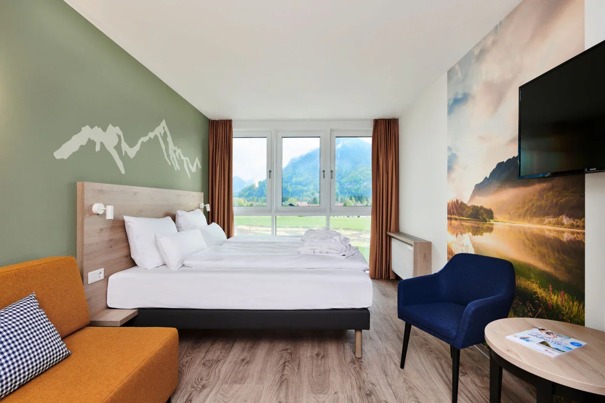 Rooms in Ruhpolding A room with a bed and chairs at the aja Hotel Ruhpolding.