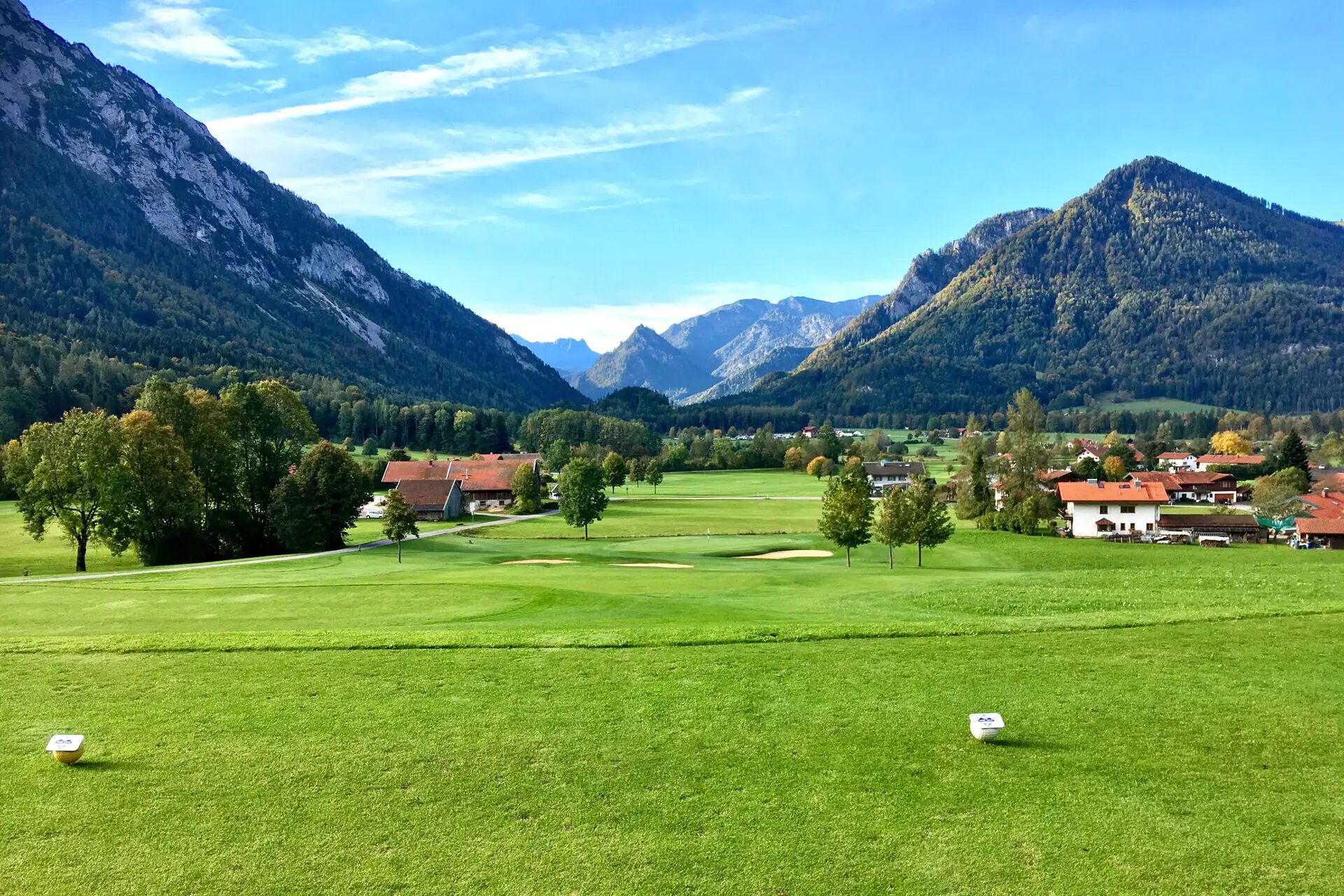 Golf course Ruhpolding Large green field with trees and mountains in the background.