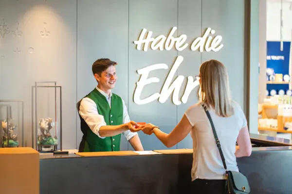 Check-in A man hands the room card to a woman at a reception desk.