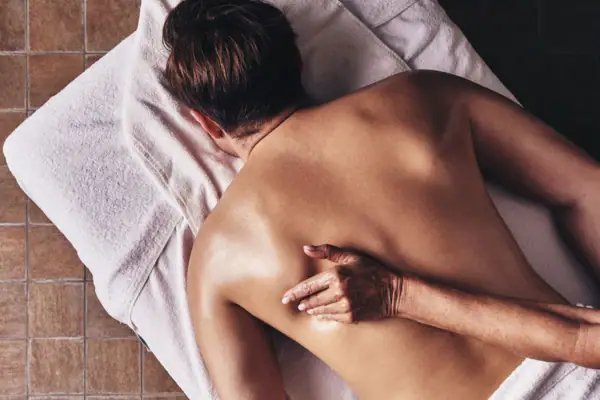 Massage Eine Person liegt auf einem Handtuch mit dem Rücken nach oben.