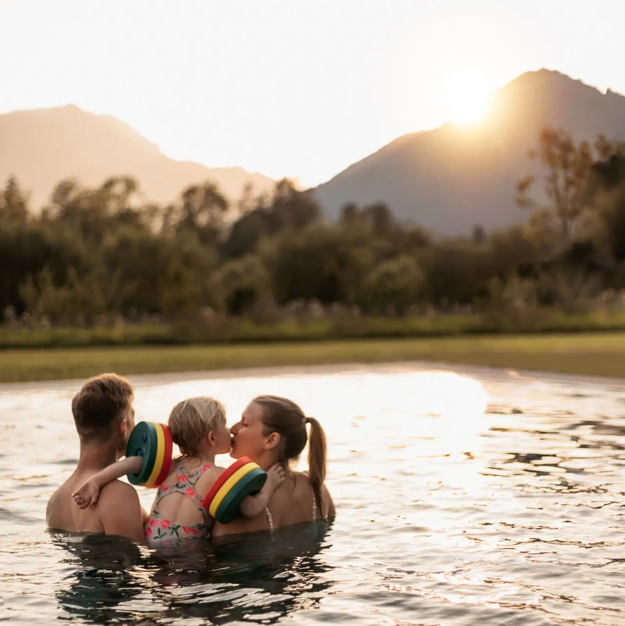 Family holidays in Ruhpolding A family in a swimming pool with mountains in the background.