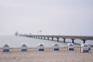 Ein Strand mit Stühlen und einem Pier.