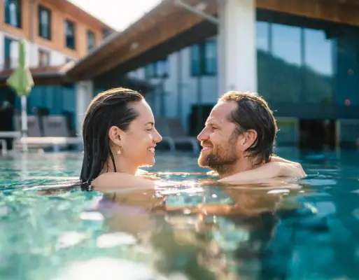 Wellness A man and a woman in the swimming pool in front of a hotel.