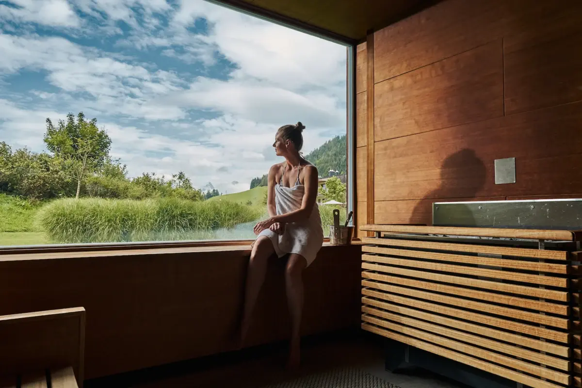 A woman sits on a windowsill and looks out of the window.