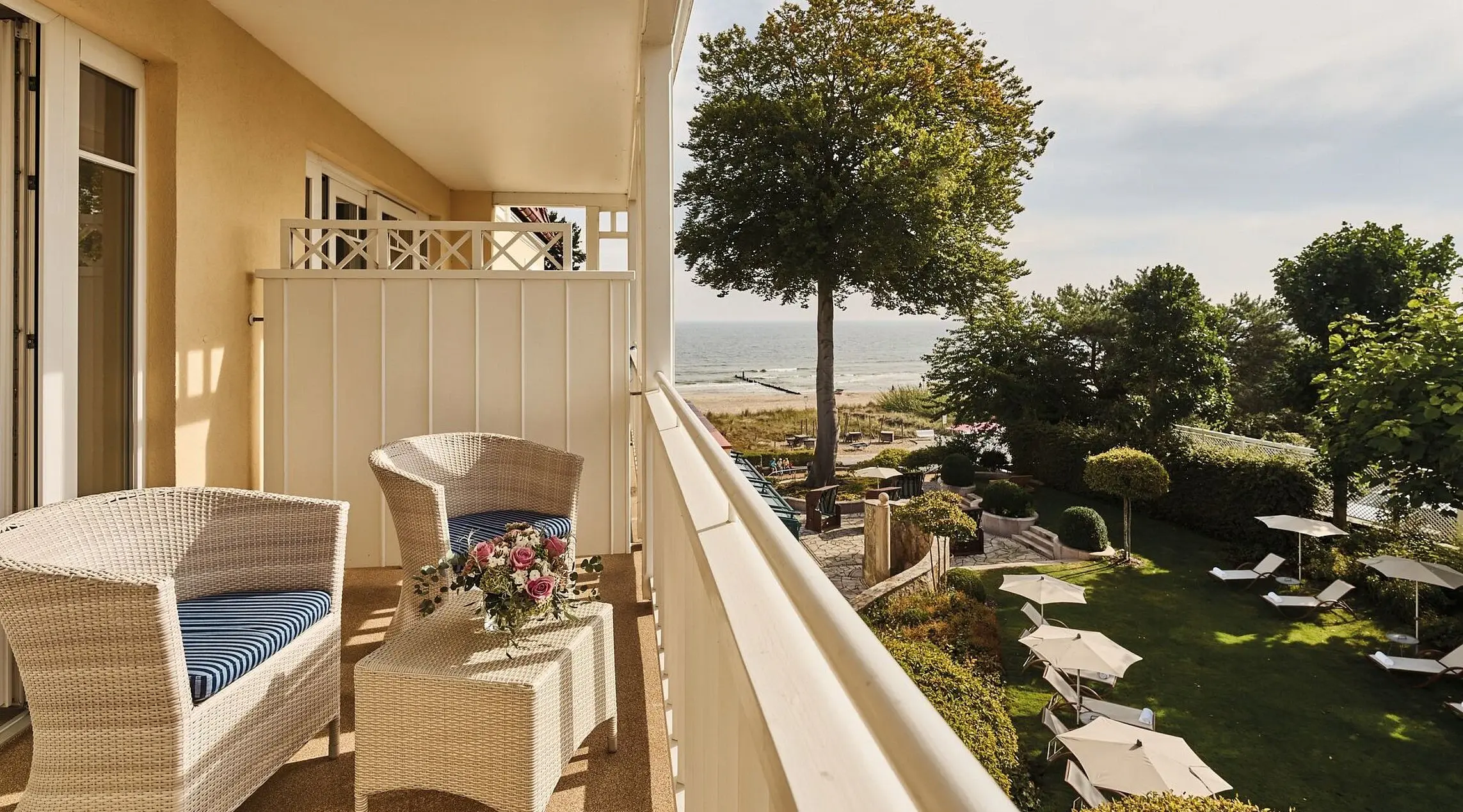 A balcony with chairs, a table and a tree in front of a building.