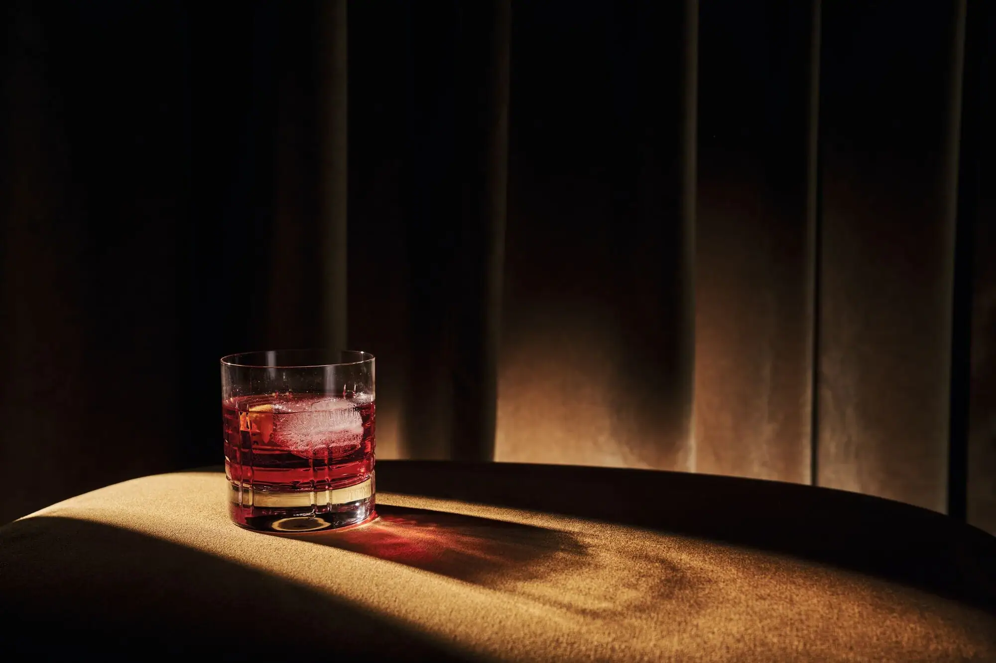 Stork Club Schlepzig A glass of red liquid and ice on a table.