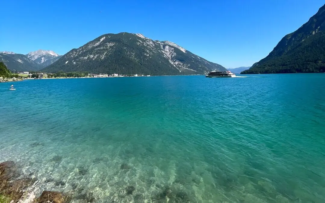 View of the blue Achensee with mountains in the background.