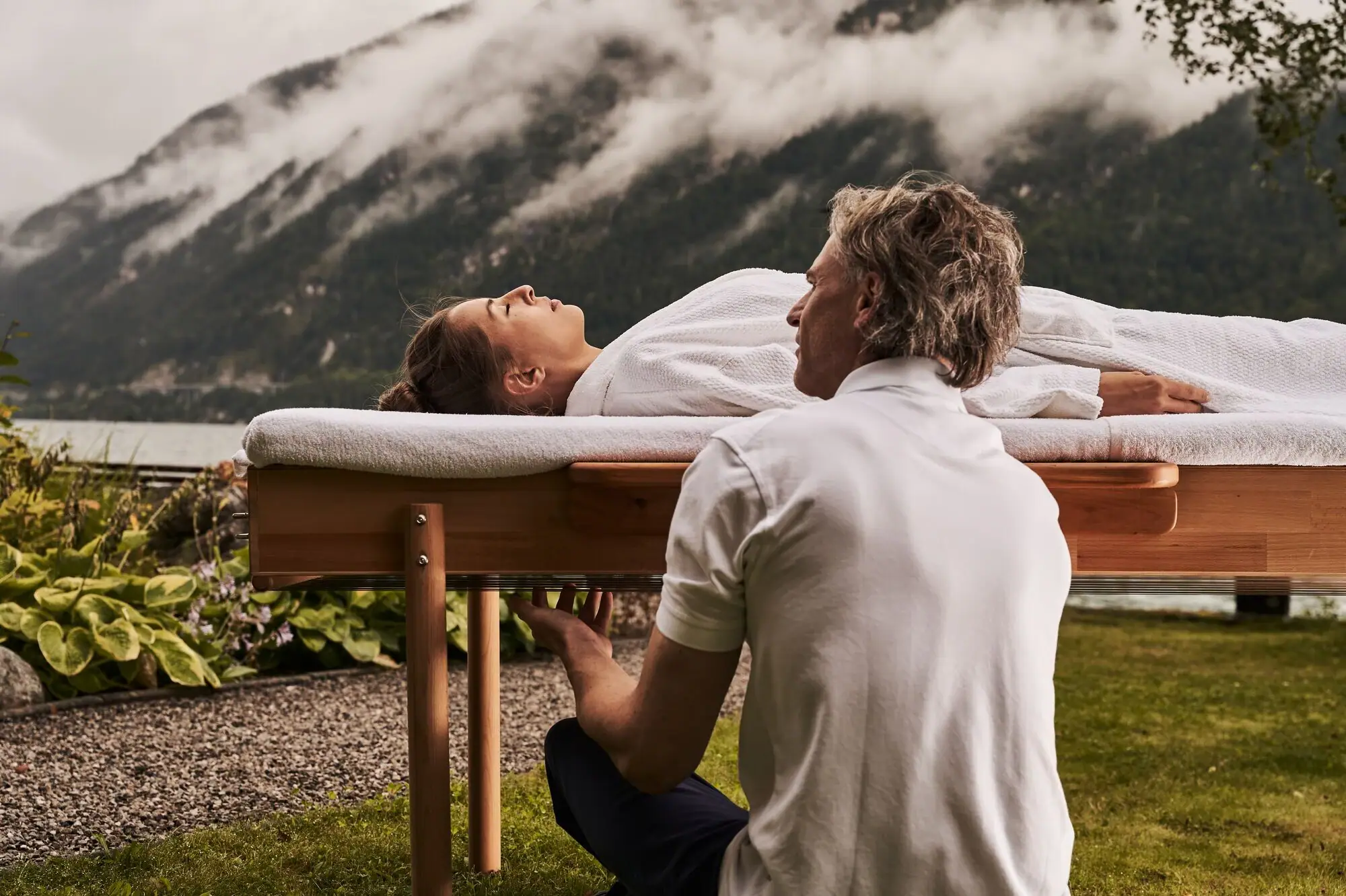 Massage A man kneels on a table on which a woman is lying.
