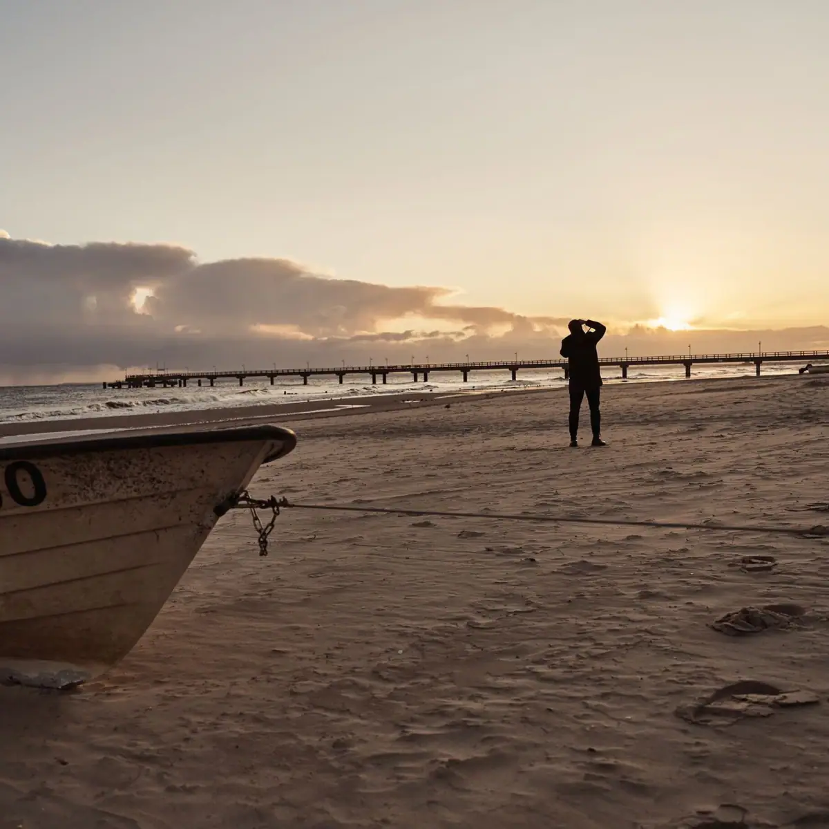 Person on the beach with boat on the shore.