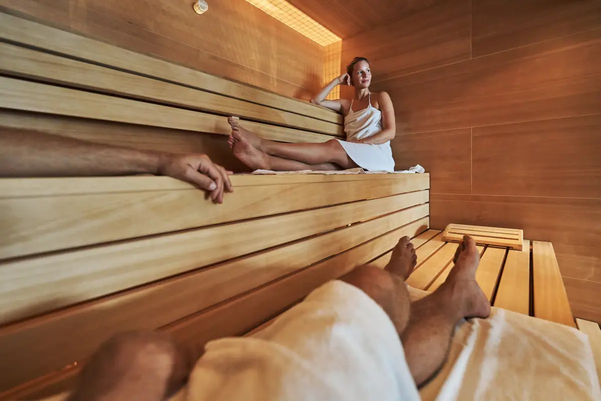 Woman sitting on a wooden bench in a sauna.