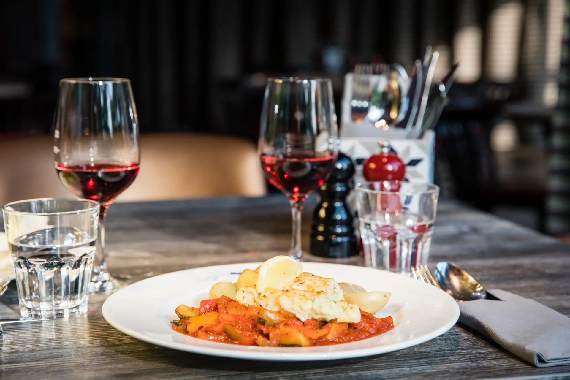 A plate of food and wine glasses on a table.