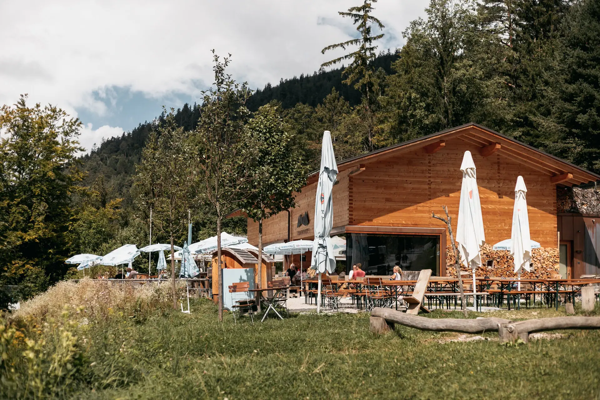 Alpine pasture in the mountains A building with tables and chairs outside, trees in the background.