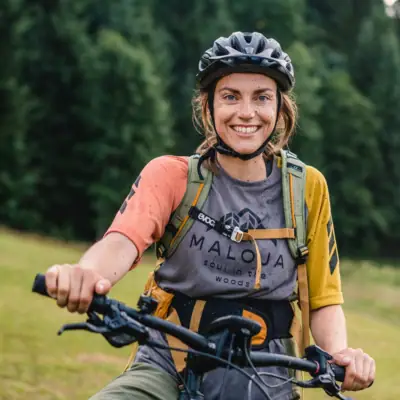 Cycling A woman rides a bicycle and smiles at the camera.