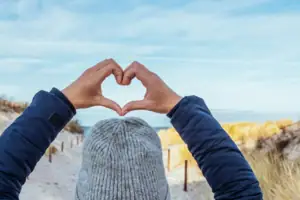 Ostsee Strand Eine Person formt mit den Händen ein Herz.