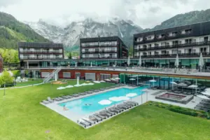 An outdoor swimming pool at a hotel, with a lawn and mountains in the background.