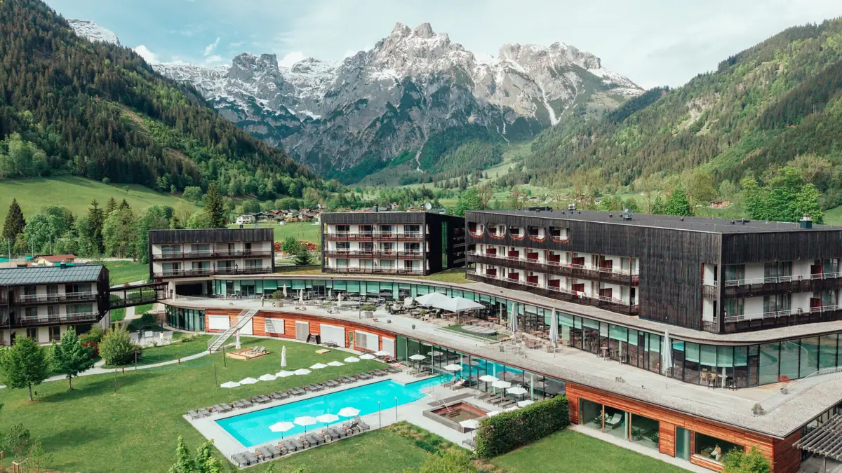 A hotel with a swimming pool and mountains in the background