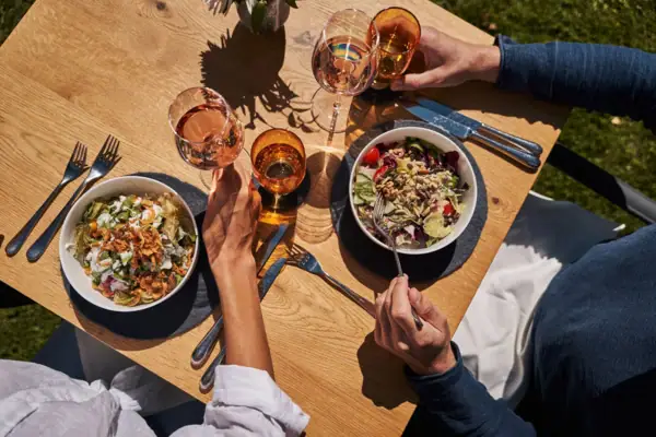 Guest garden A group of people eating at a table with food and drinks.