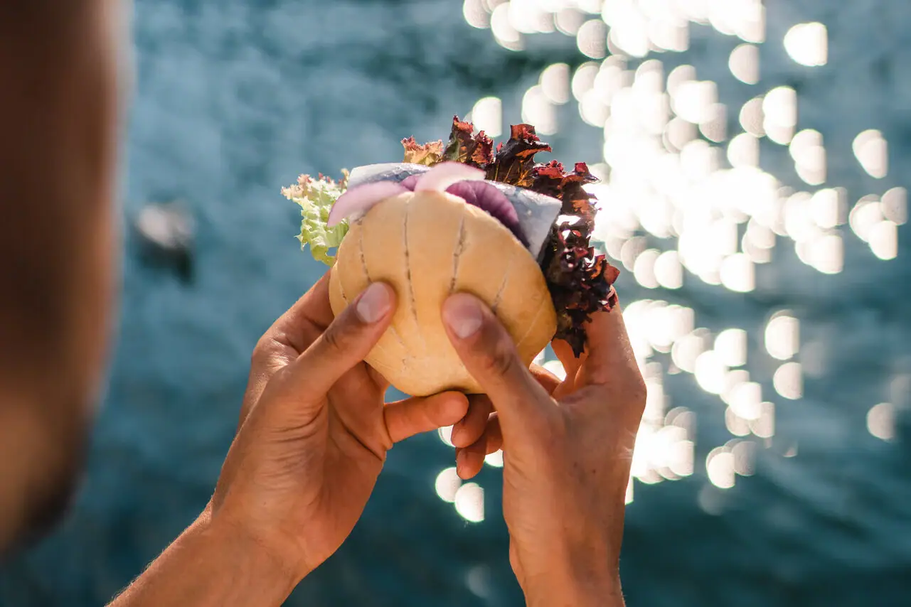 A person holds a fish roll above water.