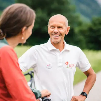 A man and a woman are smiling and chatting outside.