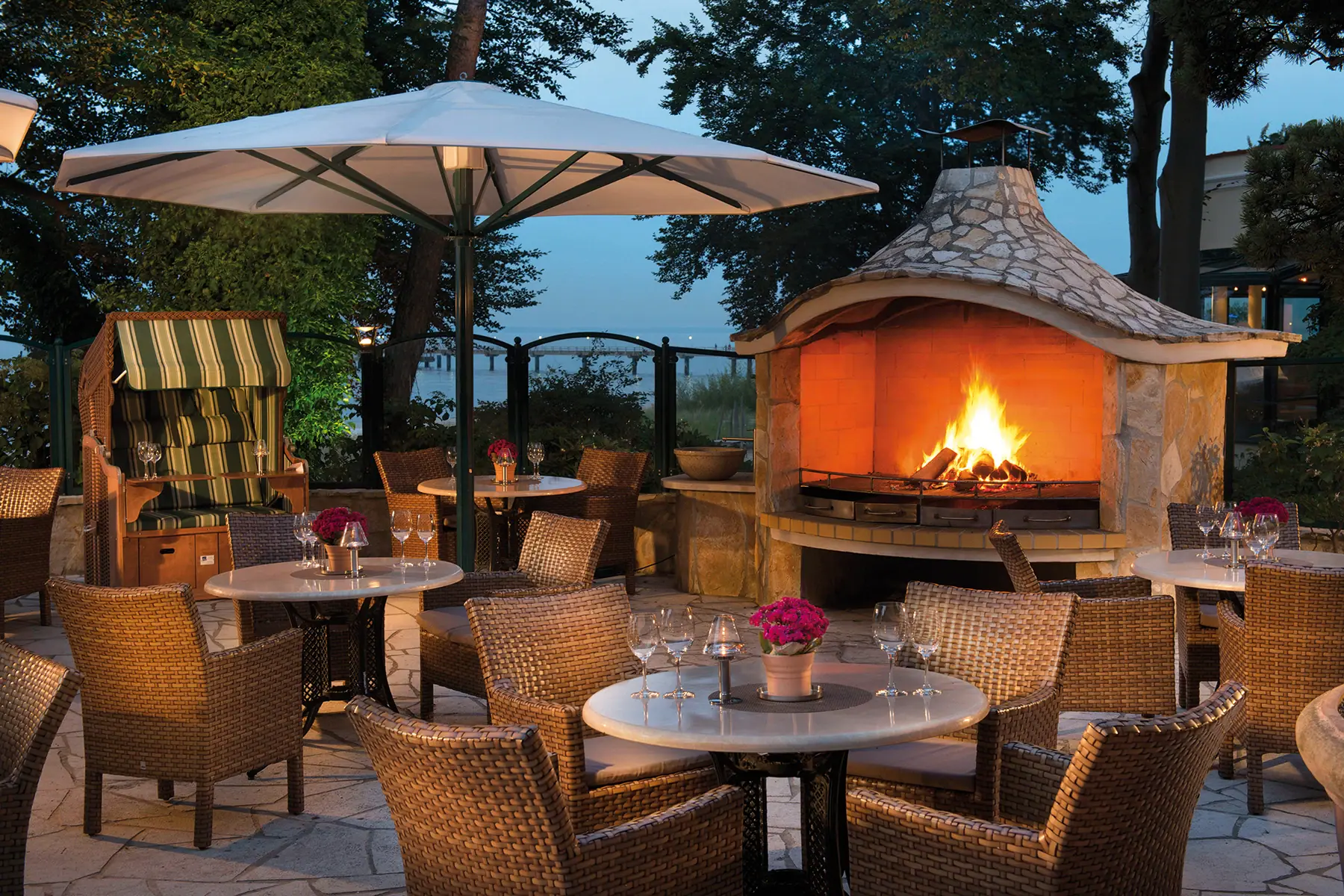 A table and chairs around a fireplace on a terrace.