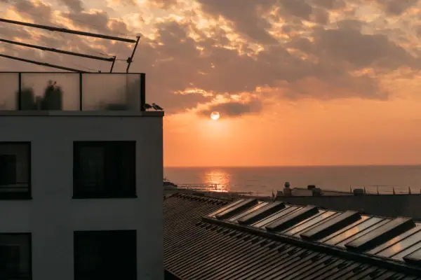 Ein Gebäude mit Dach vor einem Sonnenuntergang.