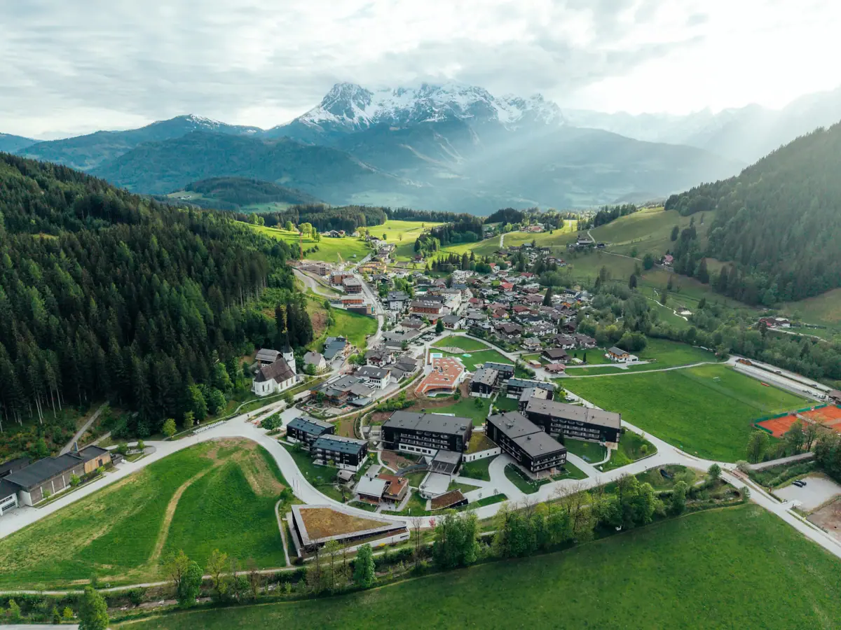 A mountain village with houses nestled amongst the trees and surrounded by mountains.