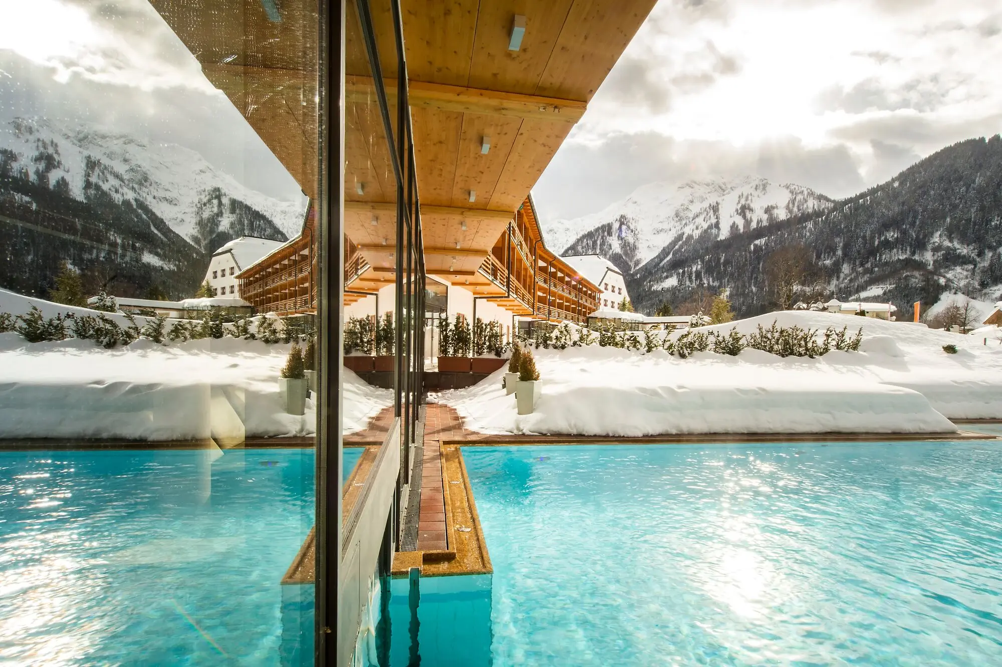Outdoor swimming pool with snow-covered mountains in the background.