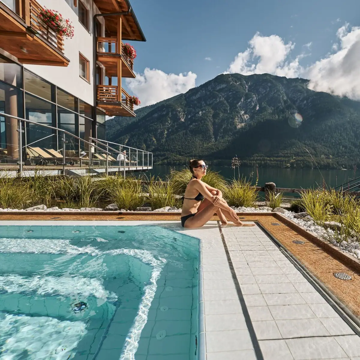 Whirlpool at Lake Achensee A woman sits by a pool with a mountain in the background.