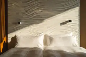 Rooms at the aja Warnemünde A bed with cushions in front of an illuminated wall.