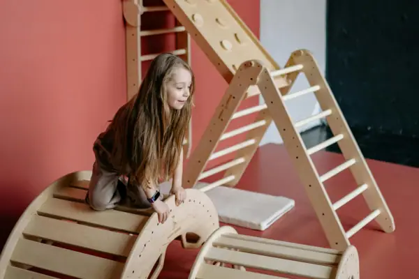 Girl climbing on a wooden toy.