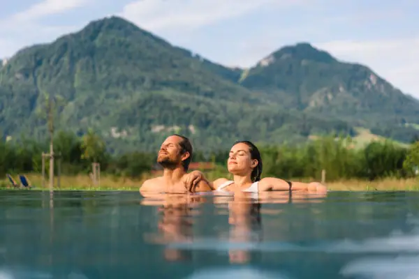 A man and a woman in a pool with mountains in the background.