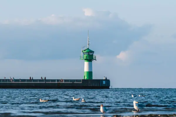 A lighthouse on a jetty against a cloudy sky.