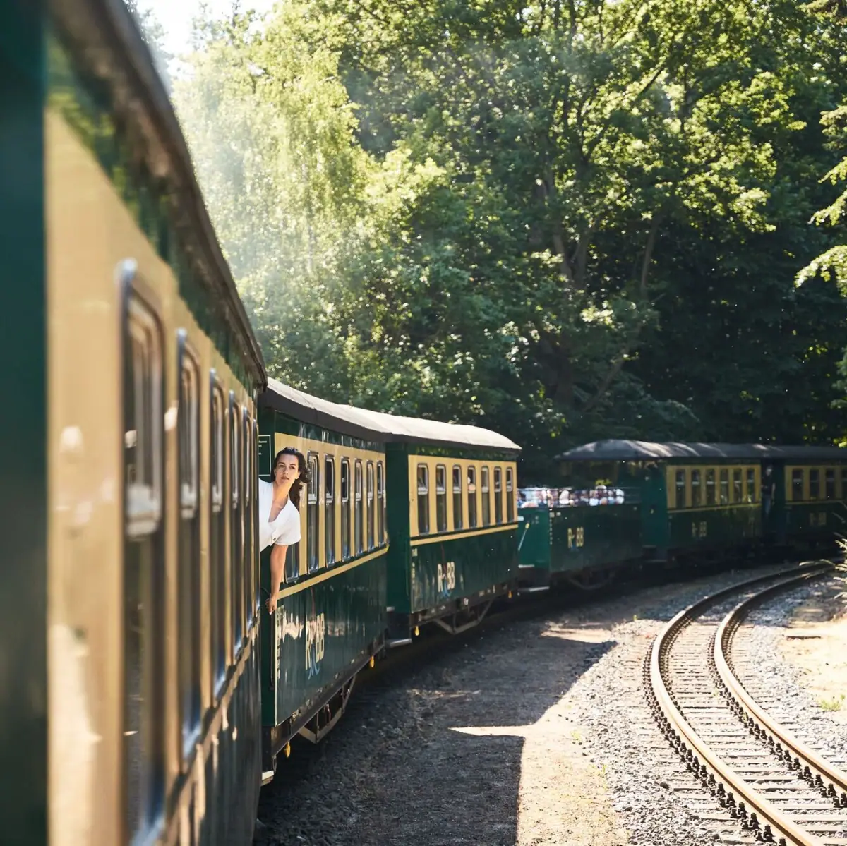 A woman leans out of a train window.