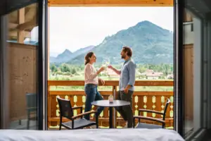 Double room mountain view with balcony aja Ruhpolding A man and a woman holding wine glasses on a balcony.